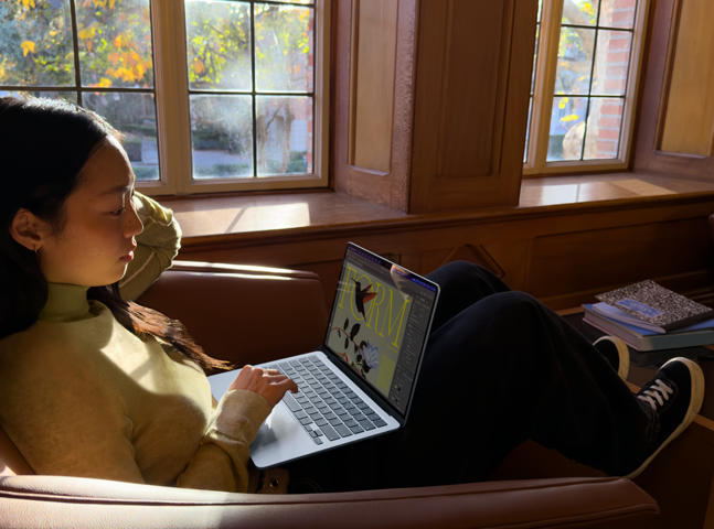 Iemand zit in een fauteuil en werkt op een MacBook Air
